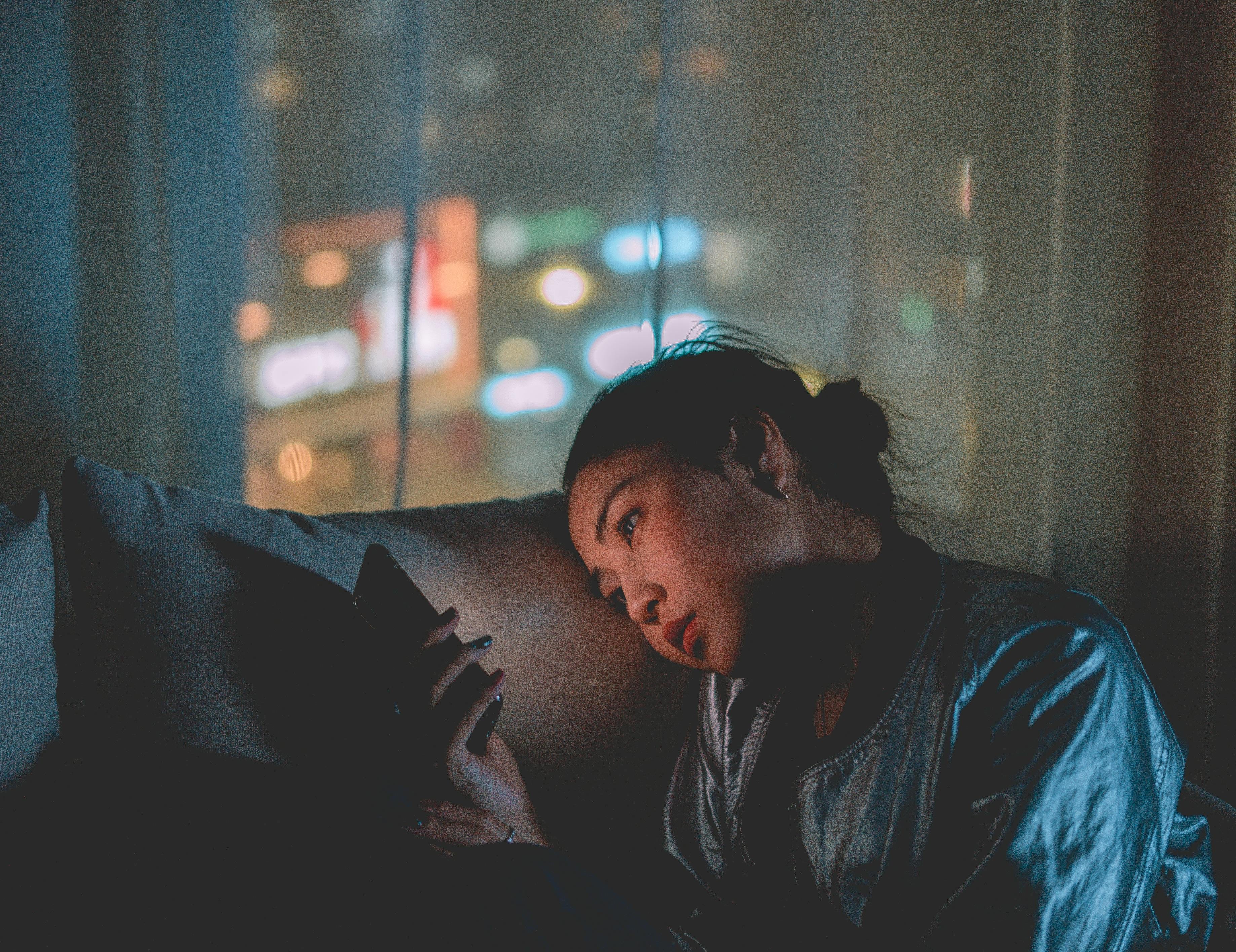 woman using smartphone at night with city lights representing global eSIM connectivity