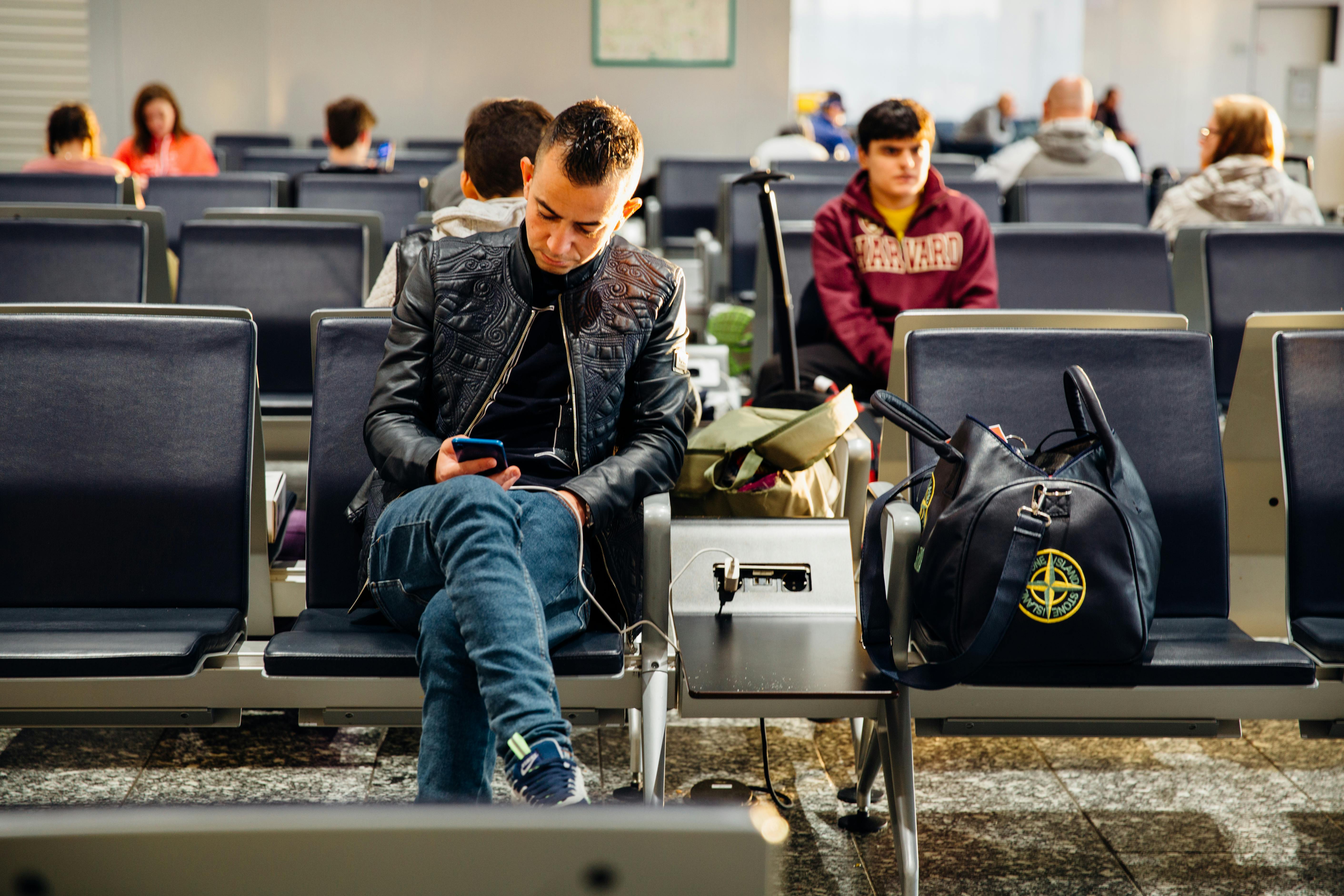man sitting in airport on mobile phone