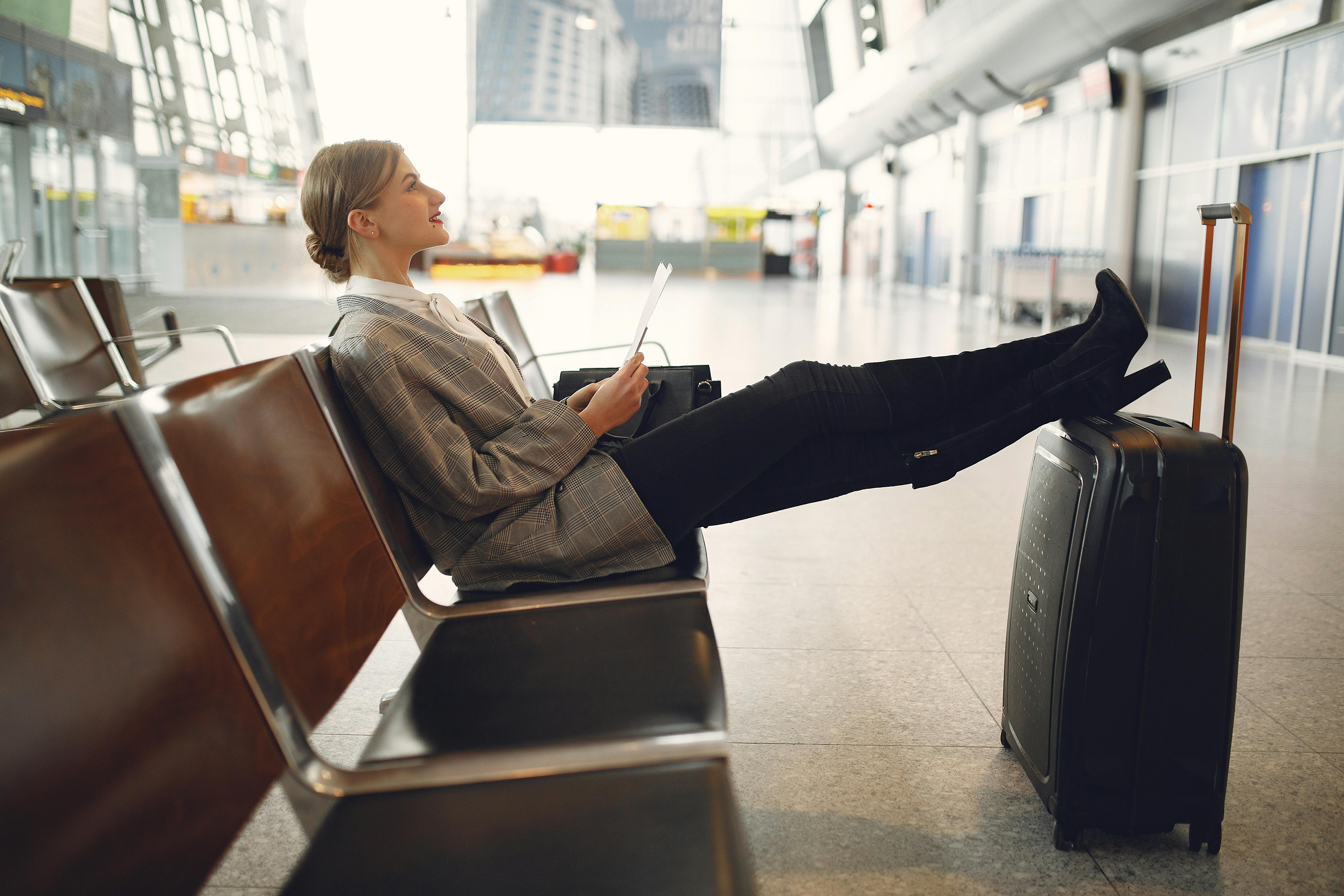 woman sitting comfortably at airport with her feet resting on luggage