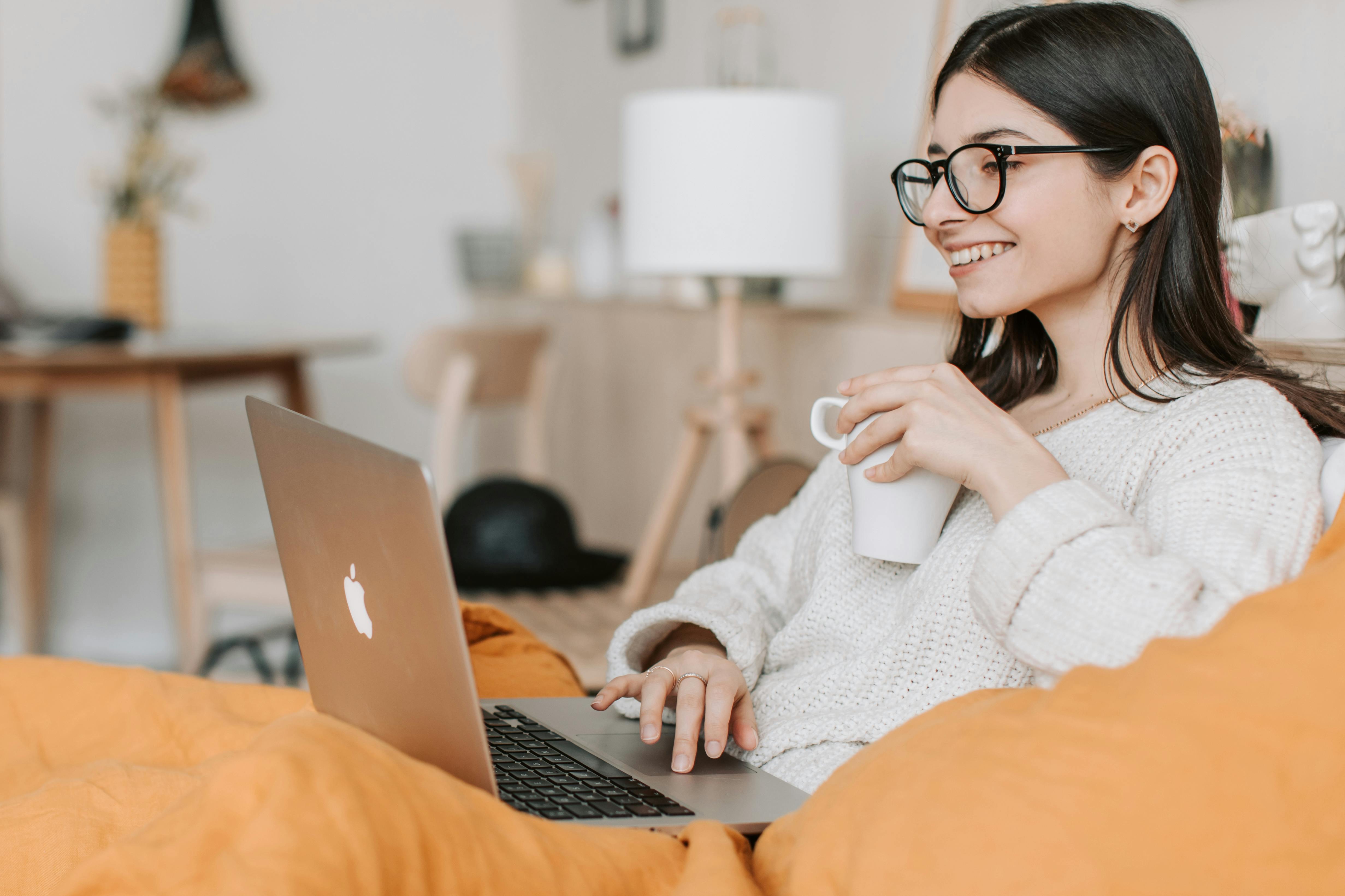 person in home office environment on MAC sipping coffee