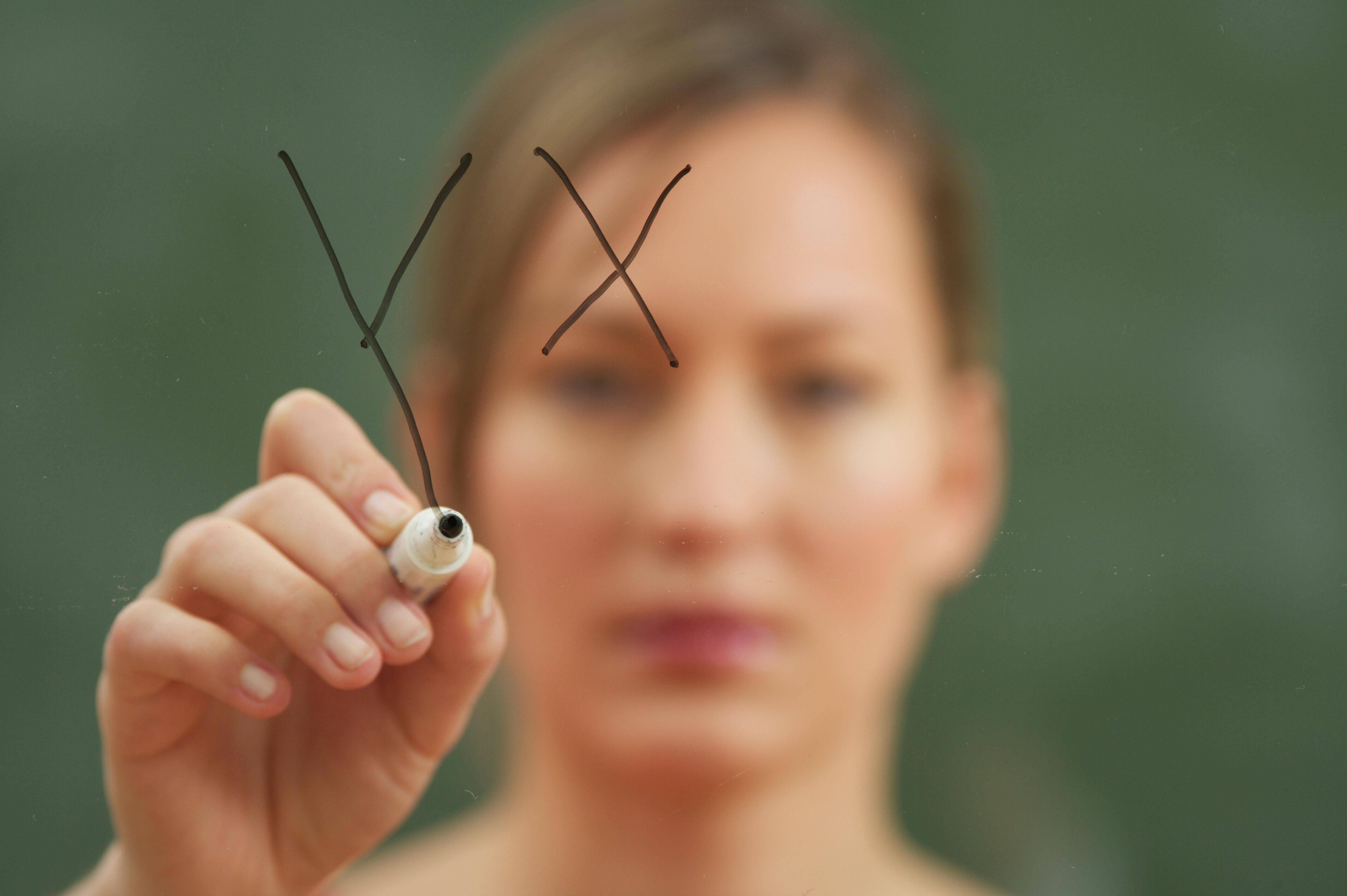 person writing a formula on a transparent board