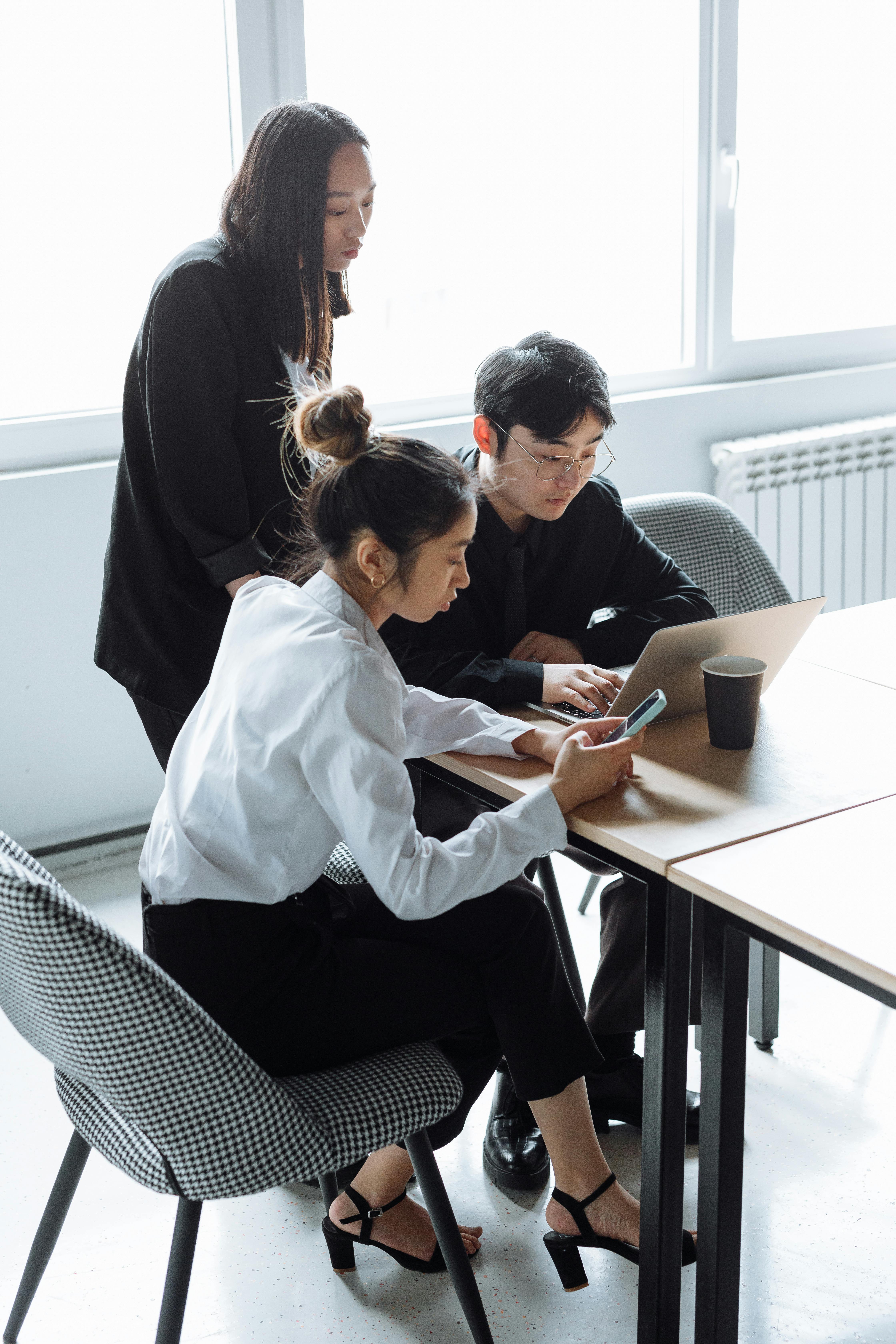 three people sitting at a table browsing on their smart phones