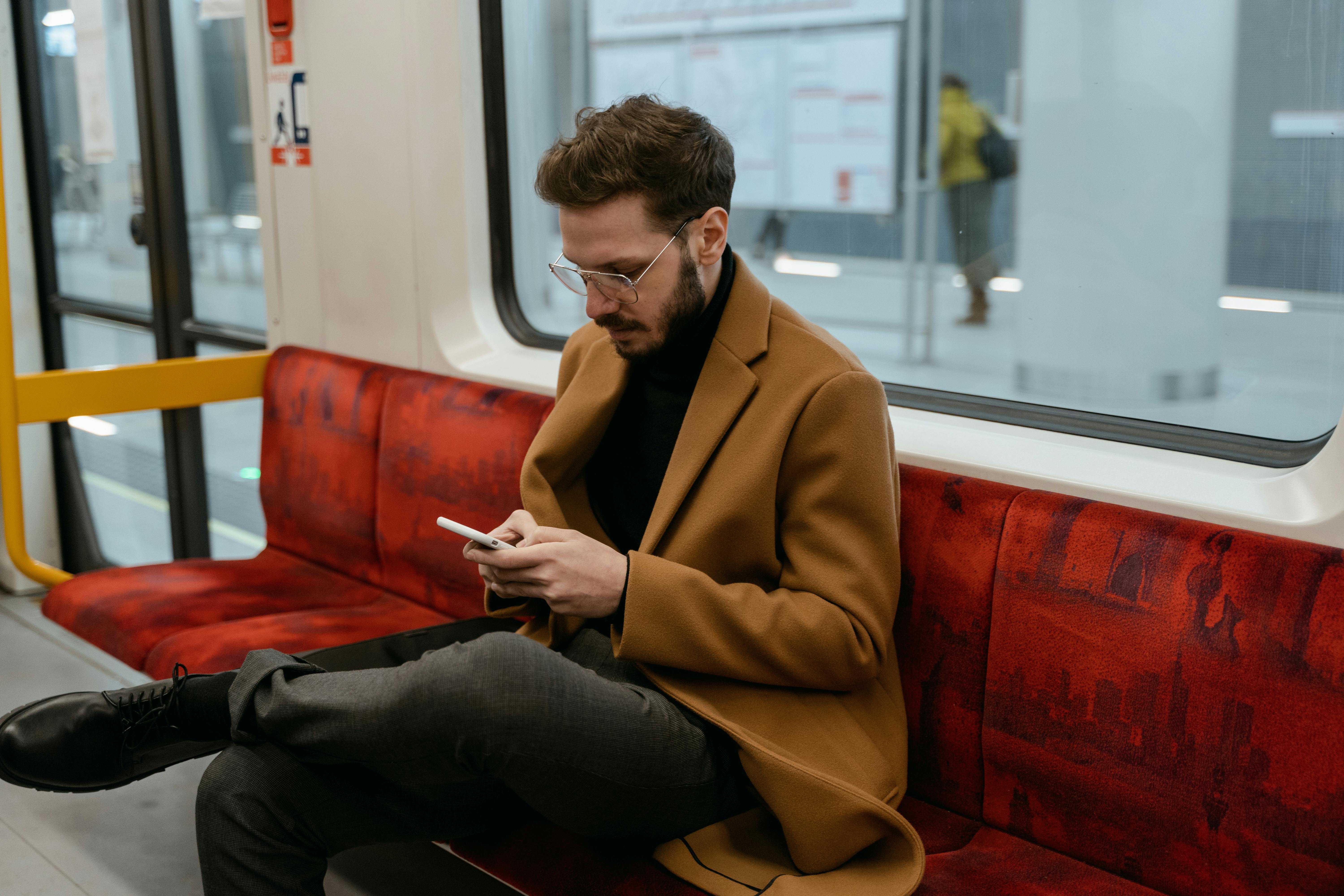 man sitting on subway/metro on his mobile phone
